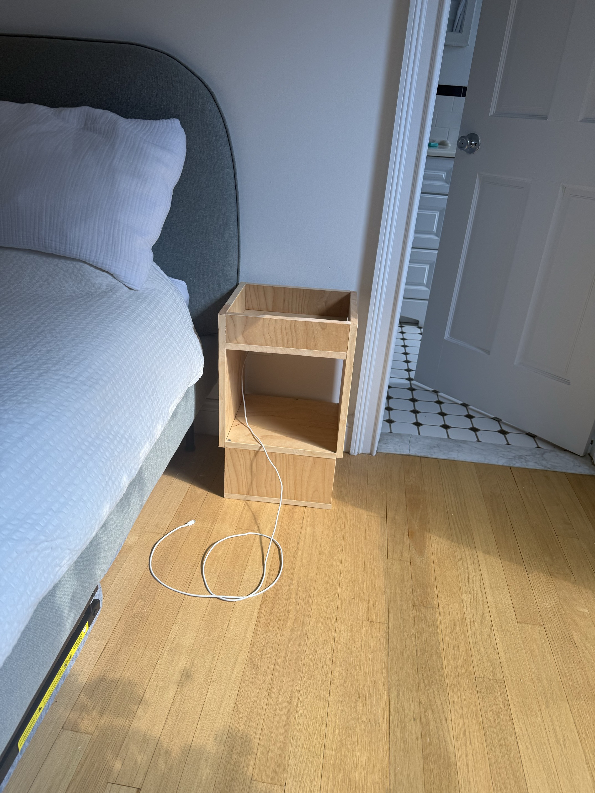 a finished plywood nightstand mounted on the wall next to a bed