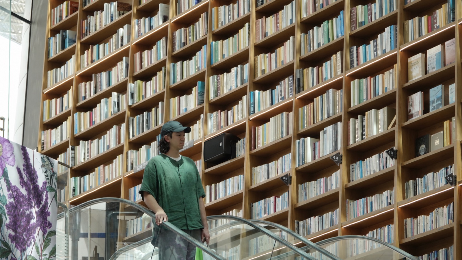 Thomas on an escalator in front of a floor-to-ceiling library wall